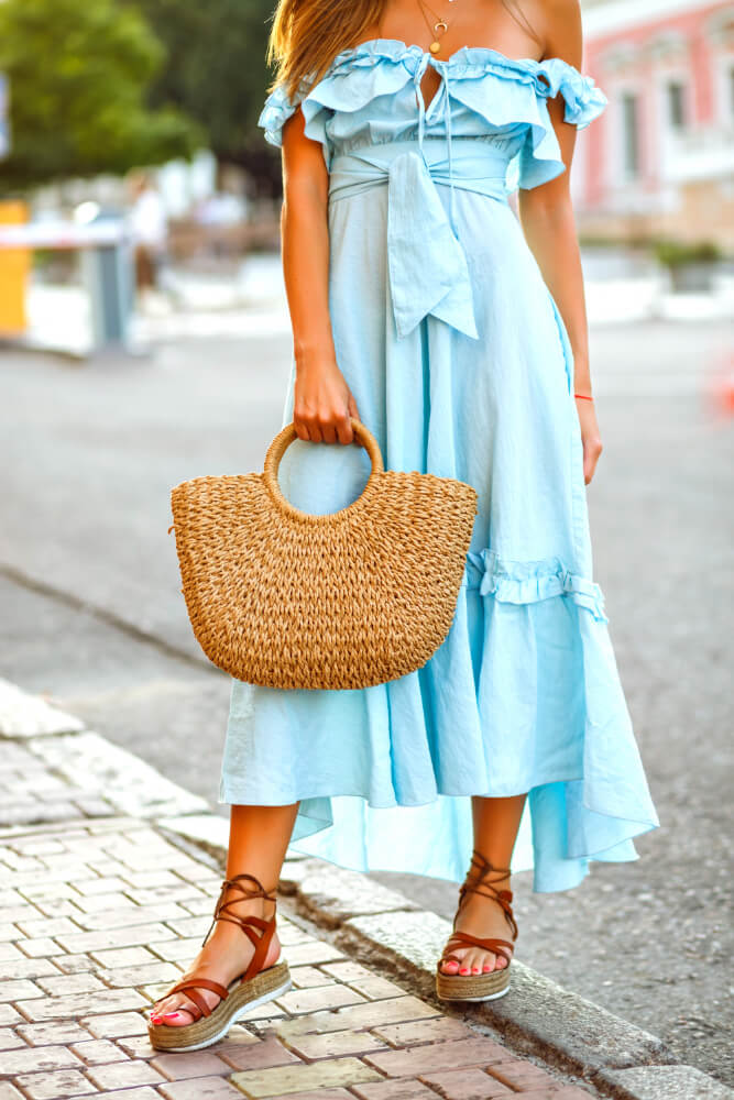 Imagem de um vestido fluido em tecido leve, acompanhado de uma bolsa de palha, ideal para um look de verão