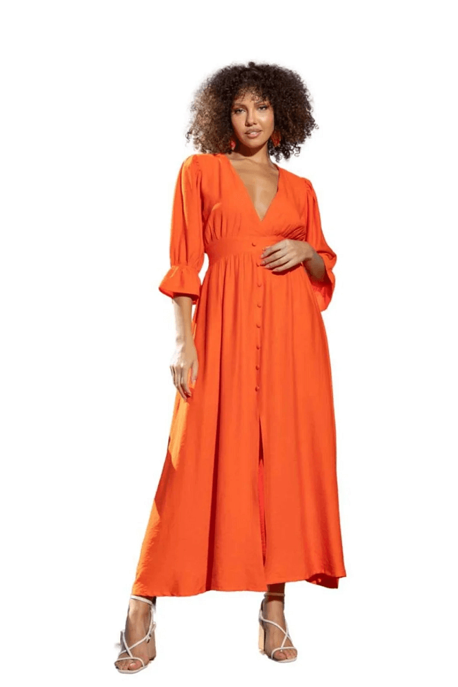 Mulher vestindo um vestido midi laranja com decote V profundo e detalhes de botões.